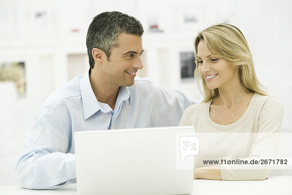Couple using laptop computer together  smiling