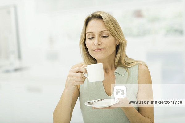 Frau hält Kaffeetasse  lächelnd