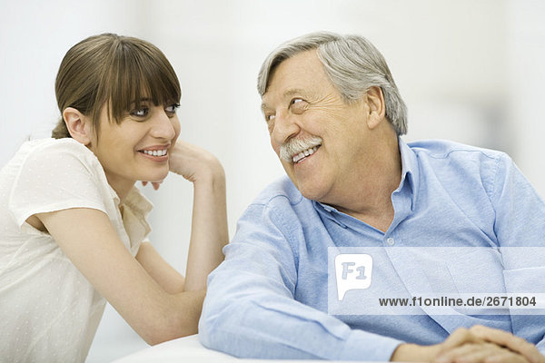 Senior man and adult daughter smiling at each other  portrait