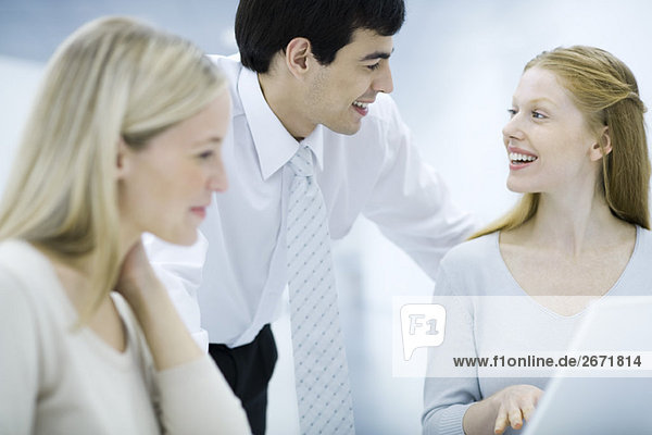 Businessman leaning over  chatting with female colleagues