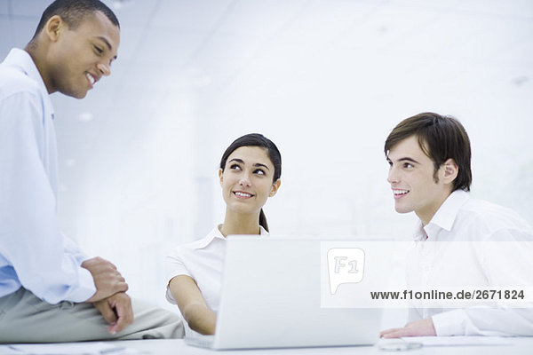 Young professionals sitting around laptop computer  smiling