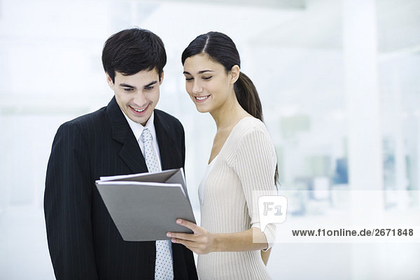 Professional woman showing male colleague document  both smiling