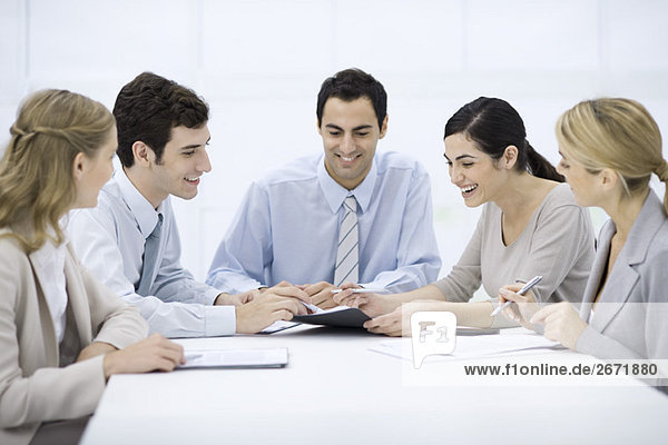 Group of professionals sitting at table  discussing document