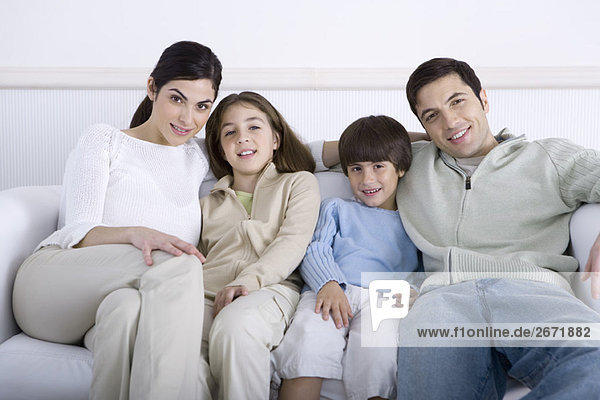 Familie sitzt zusammen auf dem Sofa  lächelt in die Kamera  Porträt