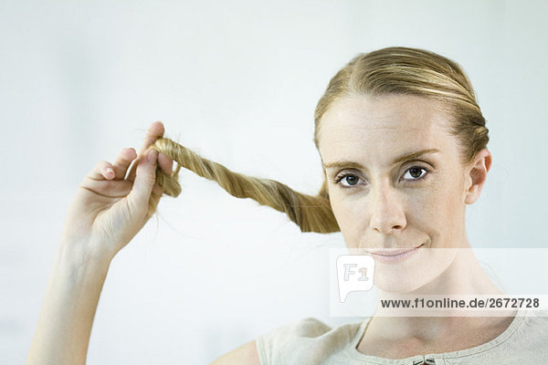 Woman twisting hair  smiling at camera  portrait