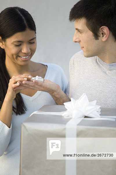 Man giving woman tiny gift  large gift in foreground