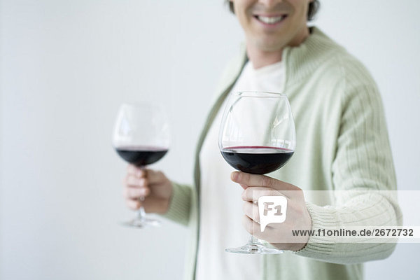 Mann hält ein Glas Wein  bietet ein zweites Glas für die Kamera  Ausschnittansicht