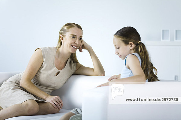 Mother and daughter seated face to face on sofa  talking