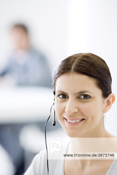 Woman wearing headset  smiling at camera  portrait