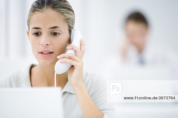 Young woman in office  using landline phone