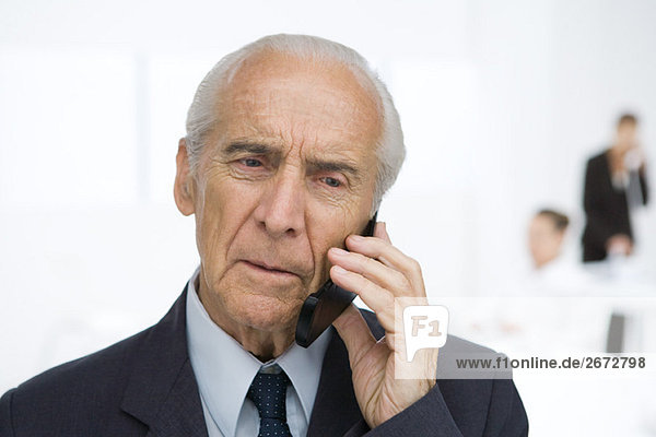 Senior businessman using cell phone  furrowing brow