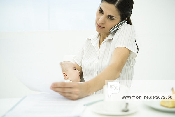 Professionelle Frau mit Handy  Baby halten  Dokument prüfen