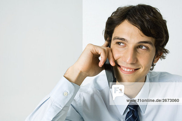 Young man using cell phone  looking away  smiling