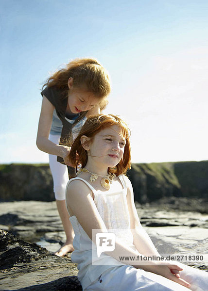Girl putting shell necklace on sister