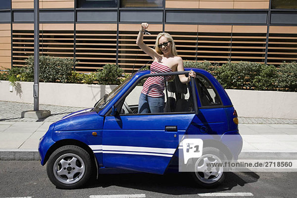 Young woman waving by electric car