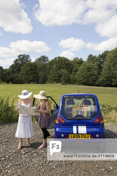 Young women with map by electric car
