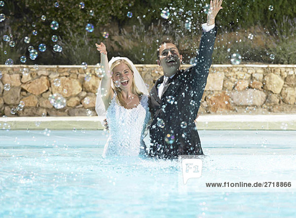 Bride and groom splashing in pool