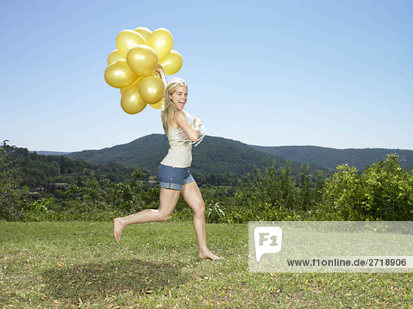 Mädchen läuft mit Luftballons