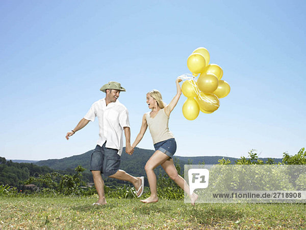Paar läuft mit Ballons