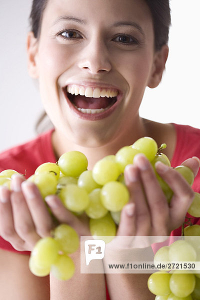 Junge Frau hält Weintraube  lacht