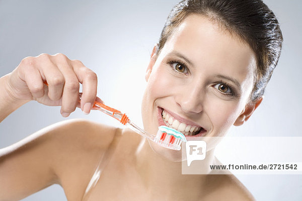 Young woman brushing her teeth  smiling  close up