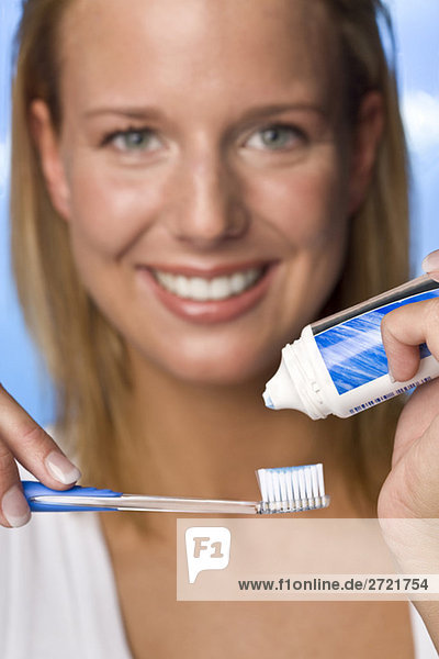 Young woman putting toothpaste on brush  portrait