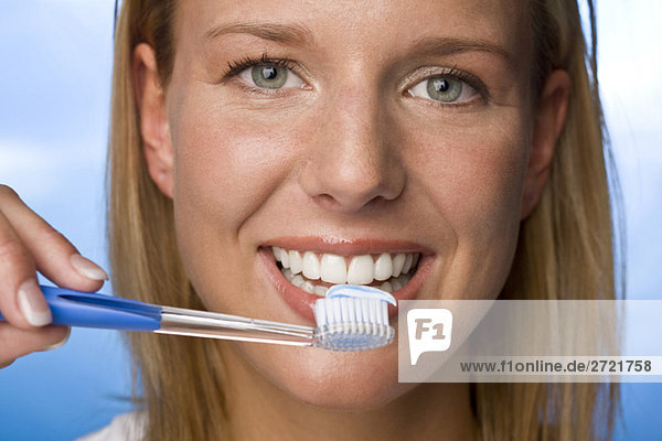 Junge Frau mit Zahnbürste  lächelnd  Portrait