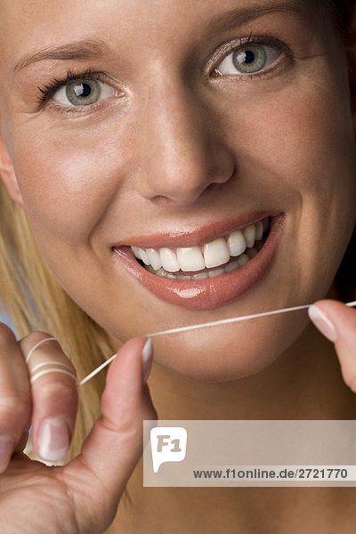 Young woman flossing her teeth  portrait  close-up