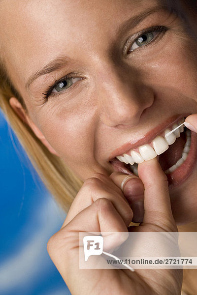 Young woman flossing her teeth  portrait  close-up