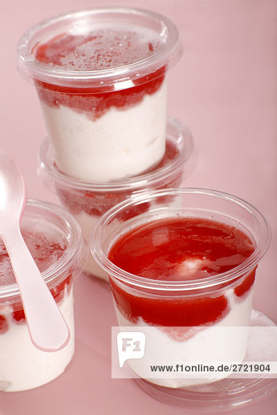 Plastikbecher mit geschichteten Erdbeer- und Joghurtdesserts