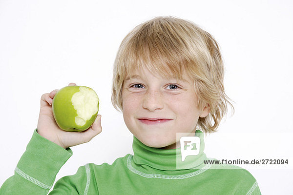 Junge (10-11) hält Apfel mit fehlendem Biss  Portrait  Nahaufnahme