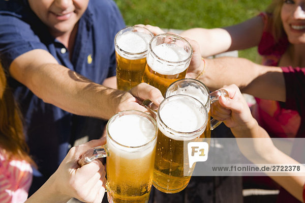 Deutschland  Bayern  Oberbayern  Fröhliche Menschen stoßen sich im Biergarten an  erhöhte Aussicht