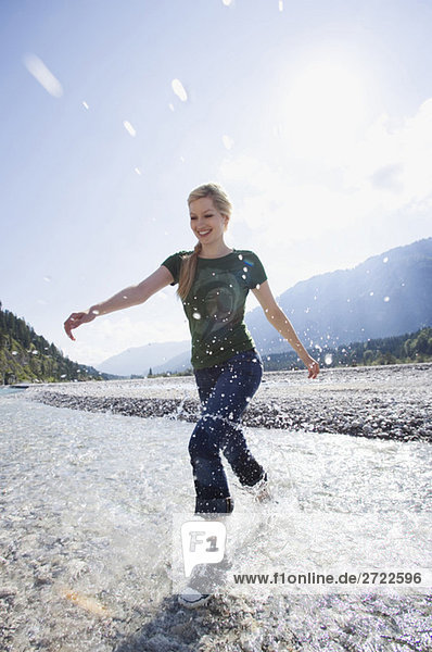Tölzer Land  Young woman running through river  smiling