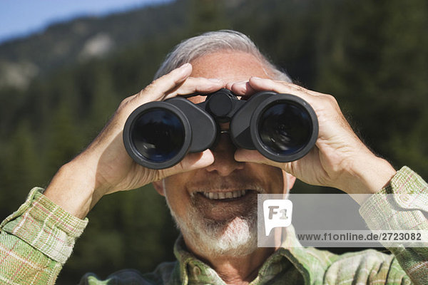 Austria  Karwendel  Senior man looking through binocular  portrait