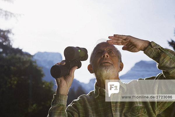 Österreich  Karwendel  Senior Mann mit Fernglas  aufblickend