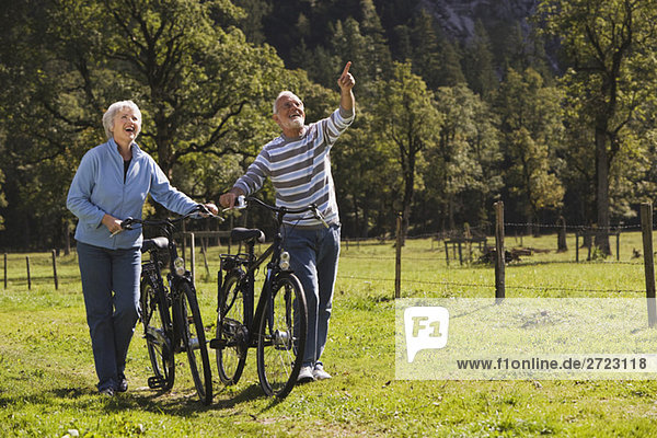 Austria  Karwendel  Senior couple pushing bikes across path