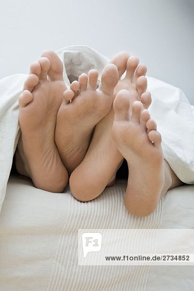 A couple's feet lying in bed