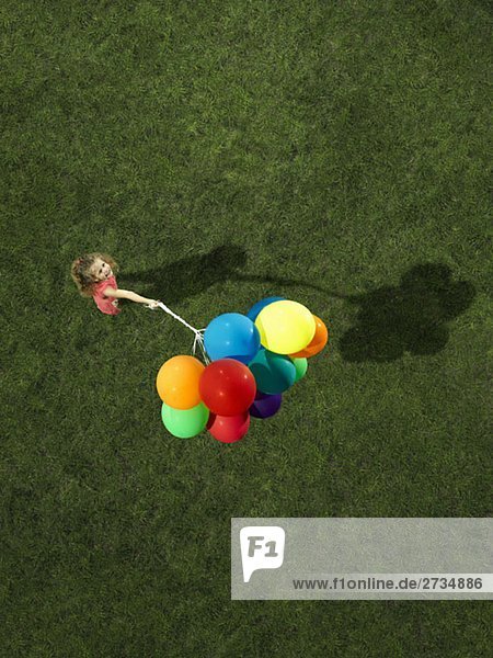 Ein Mädchen mit einem Haufen Heliumballons.