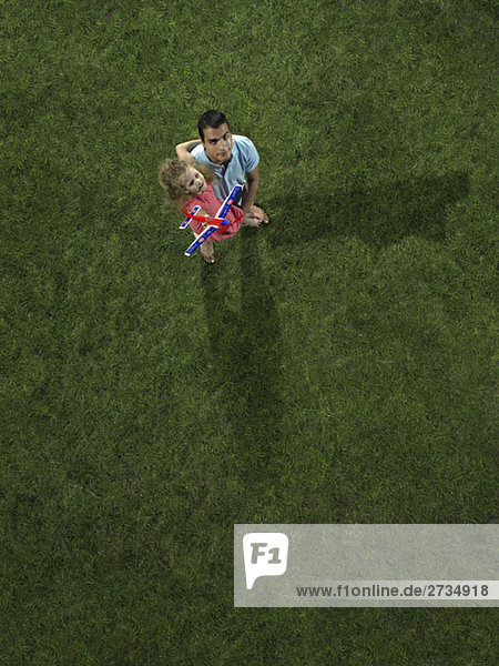 Ein Vater trägt seine Tochter mit einem Spielzeugflugzeug.