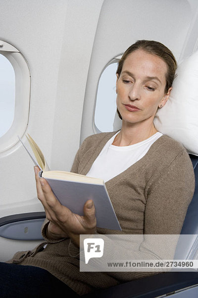 Eine Passagierin  die in einem Flugzeug liest.