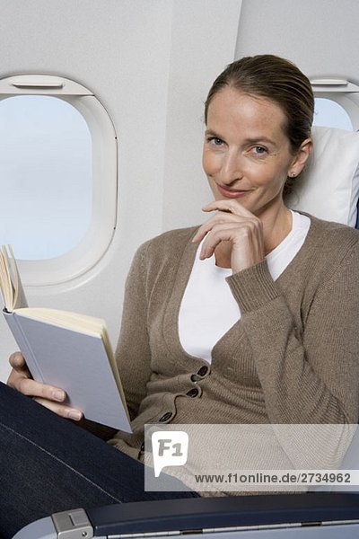 Eine Passagierin  die in einem Flugzeug liest.