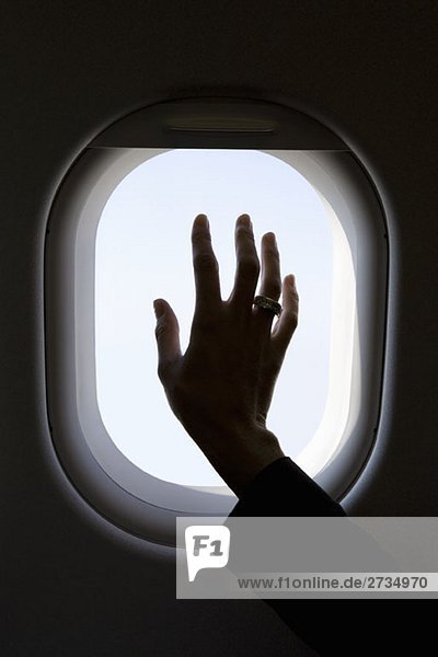 Eine Hand auf einem kommerziellen Flugzeugfenster  Silhouette