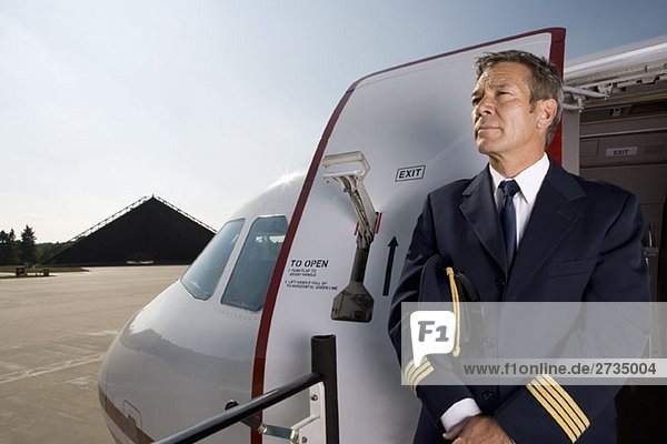 Ein Pilot  der vor der Tür eines Flugzeugs steht.