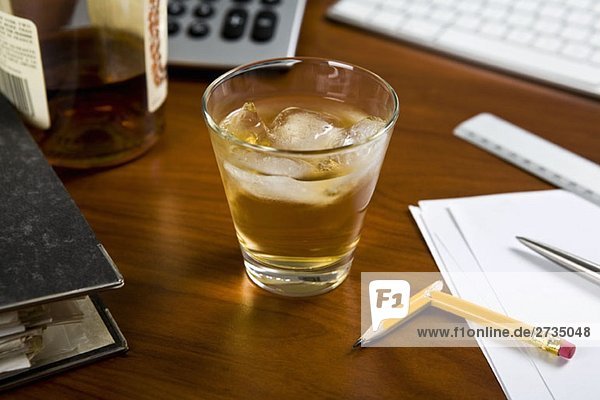 Ein Glas Whiskey und Eis auf einem Bürotisch