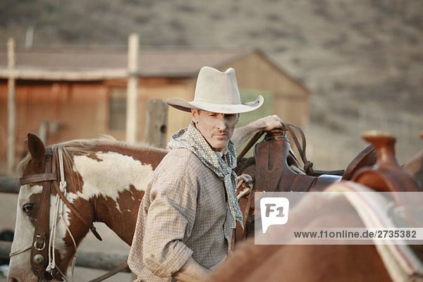 Ein Cowboy  der auf einer Ranch mit Pferden arbeitet.