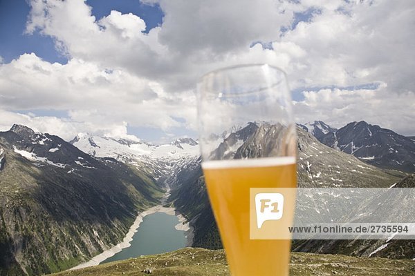 A beer glass in front of a view of the Austrian Alps
