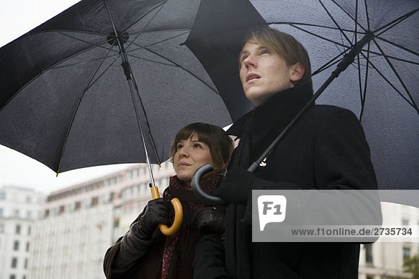 Junges Paar mit Regenschirmen