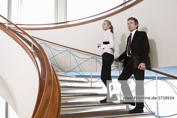 Zwei Geschäftsleute  die auf einer Treppe stehen.