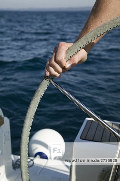Detail eines Mannes am Steuer einer Yacht