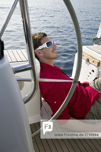 Ein Mann  der sich auf einer Yacht entspannt.